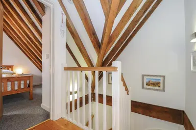 a staircase in a house with wooden beams at Stow Cottage in Camelford