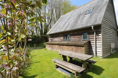 a wooden house with a bench in front of it at Stow Cottage in Camelford