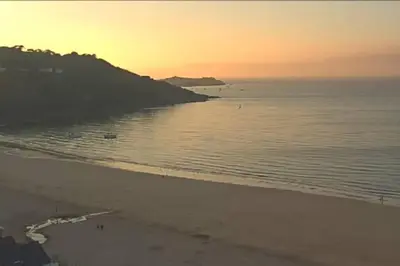 a beach at sunset with a group of people on it at Ferney Croft in Saint Erth