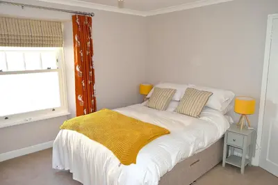 a bedroom with a bed with a yellow blanket on it at Avala in Perranporth