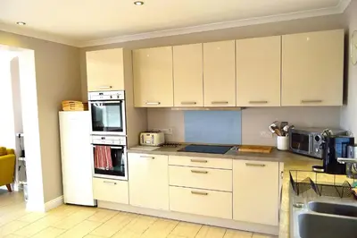 a kitchen with white cabinets and a sink at Avala in Perranporth