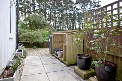 a garden with a wooden fence and some plants at Blue Bay, Marazion in Perranuthnoe