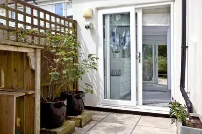 a sliding glass door on a house with potted plants at Blue Bay, Marazion in Perranuthnoe