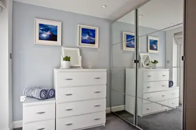 a dressing room with white dressers and a mirror at Blue Bay, Marazion in Perranuthnoe