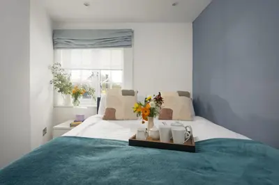 a bedroom with a bed with flowers and mugs on it at Blue Bay, Marazion in Perranuthnoe
