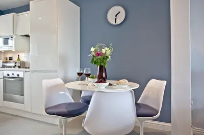 a kitchen with a table with chairs and a vase of flowers at Blue Bay, Marazion in Perranuthnoe
