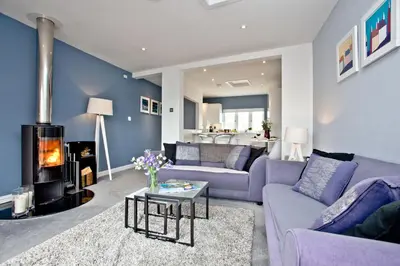 a living room with a purple couch and a fireplace at Blue Bay, Marazion in Perranuthnoe