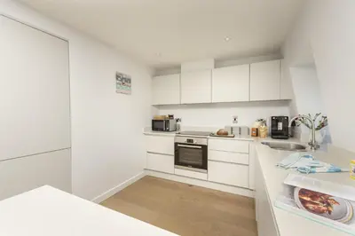 a kitchen with white cabinets and a counter top at Fowey Penthouse, Fowey in Fowey