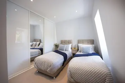 a bedroom with two beds and a mirror at Fowey Penthouse, Fowey in Fowey