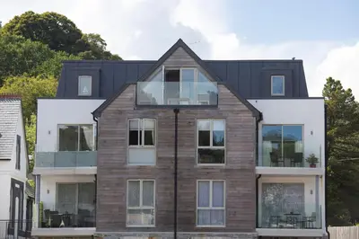 a house with glass windows and a black roof at Fowey Penthouse, Fowey in Fowey