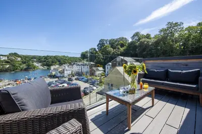 a balcony with furniture and a view of a harbor at Fowey Penthouse, Fowey in Fowey