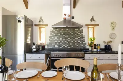 a kitchen with a table with chairs and a stove at Mowhay Barn - Woodburner & Hot tub in Padstow
