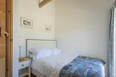 a bedroom with a white bed and a night stand at Mowhay Barn - Woodburner & Hot tub in Padstow