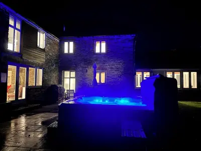 a house with a blue light in front of a building at Mowhay Barn - Woodburner & Hot tub in Padstow