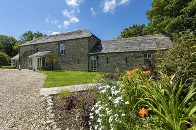 an old stone house with a garden in front of it at Mowhay Barn - Woodburner & Hot tub in Padstow
