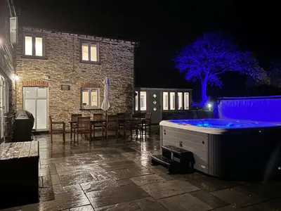 a hot tub in the yard of a house at night at Mowhay Barn - Woodburner & Hot tub in Padstow