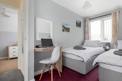 a bedroom with two beds and a desk with a laptop at Cornish Holiday - 100 Hengar Manor in Bodmin