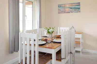 a white dining room with a table and chairs at Cornish Holiday - 100 Hengar Manor in Bodmin