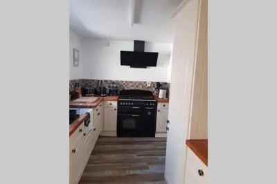 a kitchen with white cabinets and a black stove at Beautiful Cottage in Central St Columb Major in Saint Columb Major