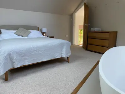 a bedroom with a bed and a dresser and a door at Beautifully Converted Chapel in Blisland