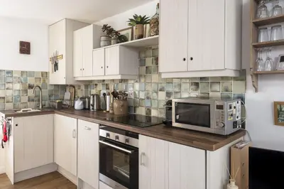 a kitchen with white cabinets and a microwave at 3 Victoria House in St Ives