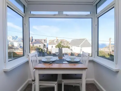 a table and two chairs in a room with windows at The Beach Hut in St Ives