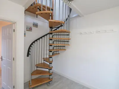 a spiral staircase in a home with white walls at The Beach Hut in St Ives