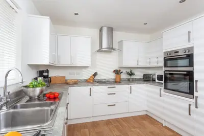 a kitchen with white cabinets and stainless steel appliances at Endymion in Porthtowan