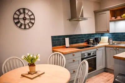 a kitchen with a table and chairs and a clock on the wall at Lower Trengale Farm Holiday Cottages in Liskeard