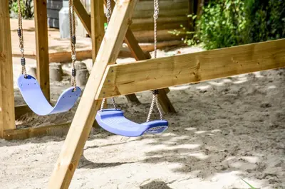 a swing set with two swings in a playground at Lower Trengale Farm Holiday Cottages in Liskeard