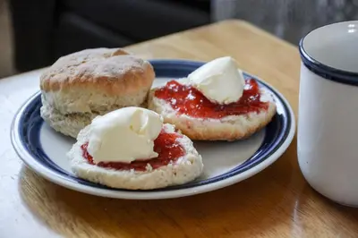 a plate with two pastries with jam and butter on it at Lower Trengale Farm Holiday Cottages in Liskeard