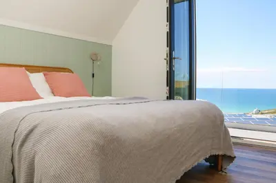 a bedroom with a bed and a large window at Pepperpots in Newquay