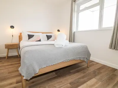 a white bedroom with a bed with pillows and a window at Pepperpots in Newquay
