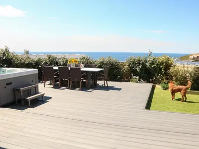 a deck with a table and a dog standing on it at Pepperpots in Newquay
