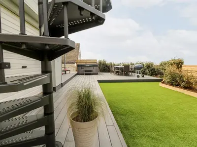 a patio with a lawn and a grill on a house at Pepperpots in Newquay