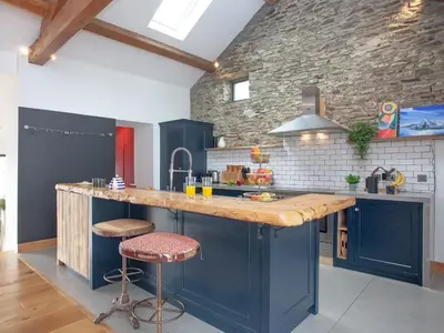 a kitchen with blue cabinets and a stone wall at Vredehoek in Quethiock