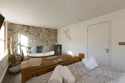 a bedroom with a bed and a stone wall at Penhaven in St Ives