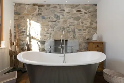 a bath tub in a room with a stone wall at Penhaven in St Ives