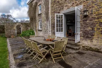 a patio with a table and chairs in front of a building at The Manor House at Boconnion in Bodmin