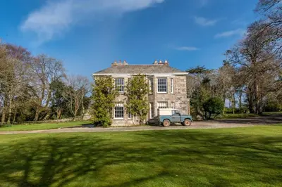 a blue truck parked in front of a large house at The Manor House at Boconnion in Bodmin