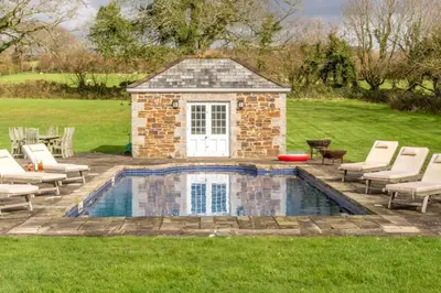 a swimming pool with chairs and a building at Boconnion Estate Sleeps up to 45 in Bodmin