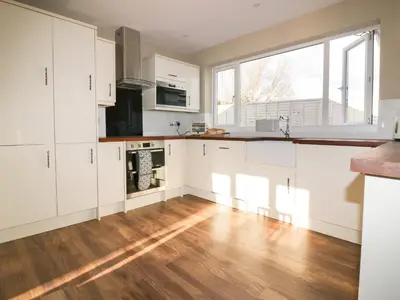 a kitchen with white cabinets and a hardwood floor at Crantock Lodge in Newquay
