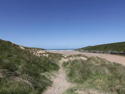 a dirt path leading to a sandy beach at Crantock Lodge in Newquay