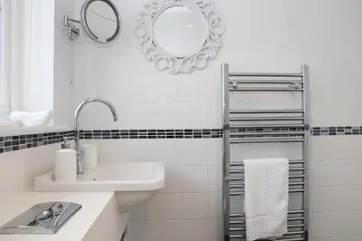 a white bathroom with a sink and a mirror at NEAR BEACHES, contemporary home in village centre in St Merryn