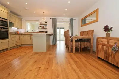 a kitchen with wooden floors and a table with chairs at NEAR BEACHES, contemporary home in village centre in St Merryn