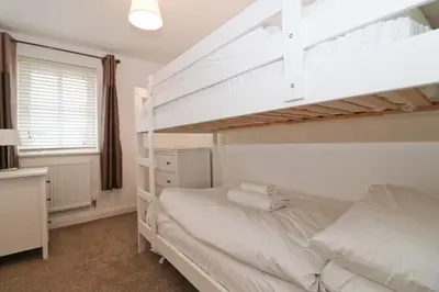 a bedroom with two bunk beds and a desk at NEAR BEACHES, contemporary home in village centre in St Merryn