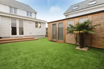 a backyard with a green lawn and a house at NEAR BEACHES, contemporary home in village centre in St Merryn