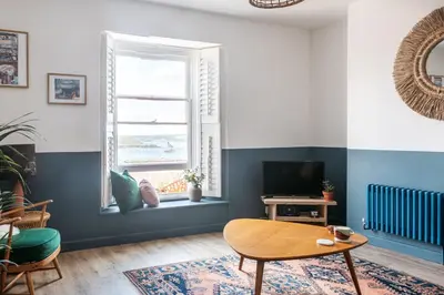 a living room with a table and a window at Stunning views over the beautiful Falmouth Harbour in Falmouth