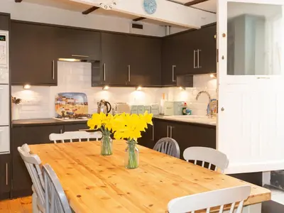 a kitchen with a wooden table with yellow flowers on it at The Sail Loft in St Ives