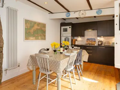 a dining room with a table and chairs and a kitchen at The Sail Loft in St Ives